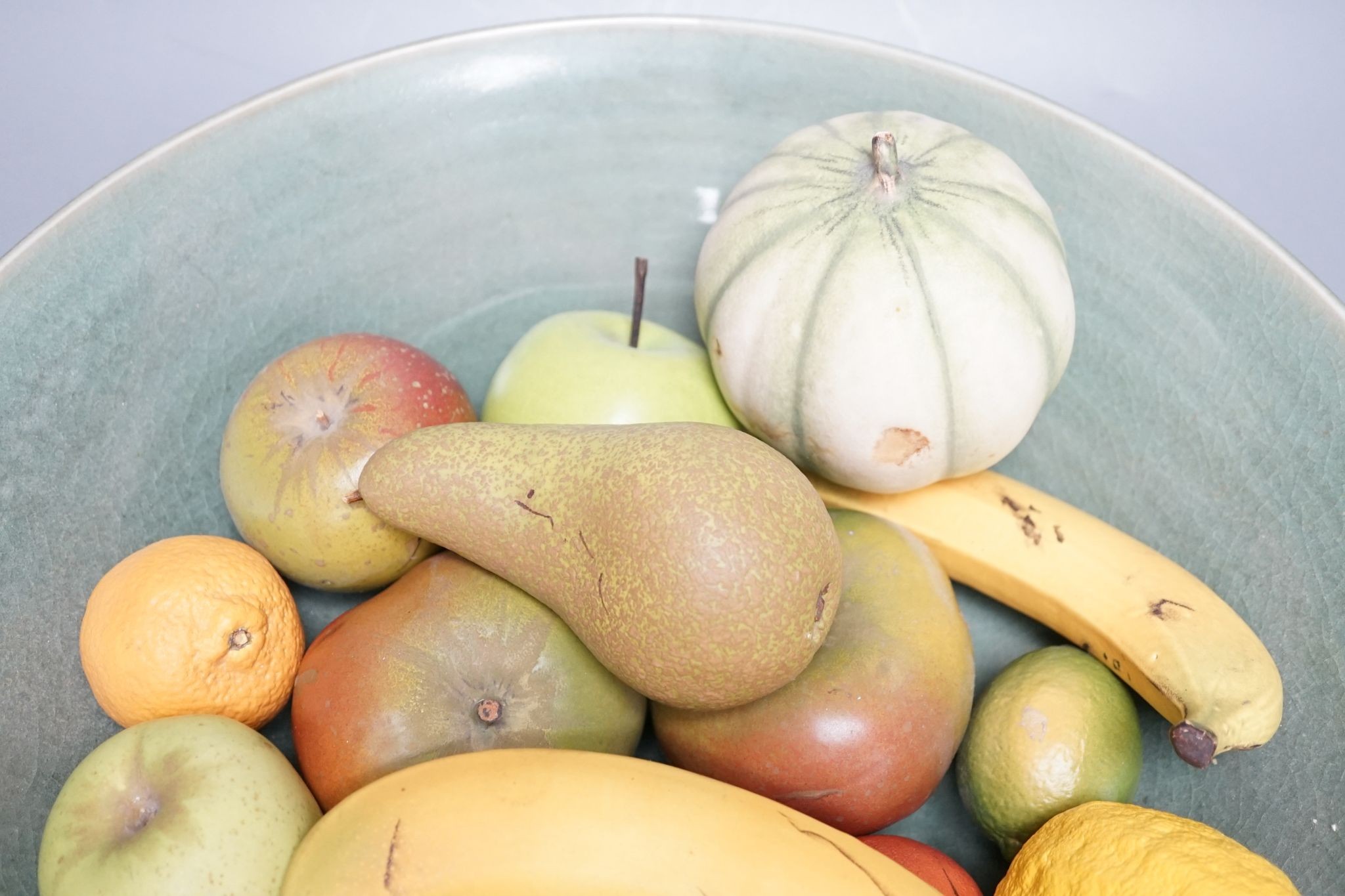 A collection of vintage Penkridge ceramic fruit including a pomegranate, melon, two bananas, limes, lemon, pear etc (18 items) in a green ceramic bowl, 42cm diameter